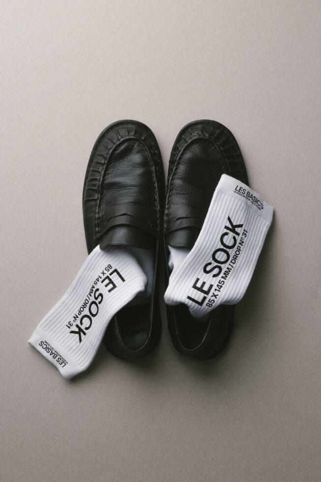 Black loafers paired with white ribbed crew socks displaying text overlay