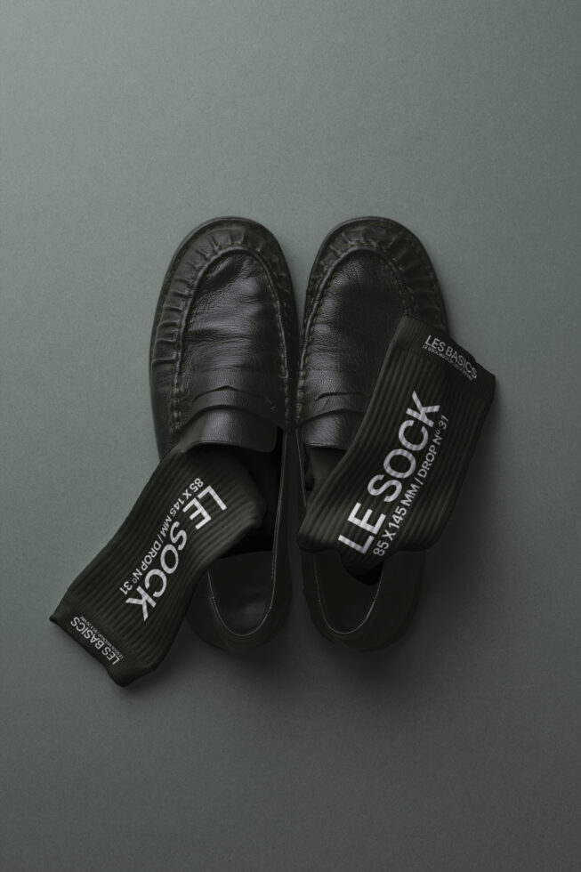 Black leather loafers styled with black ribbed socks showing white branding