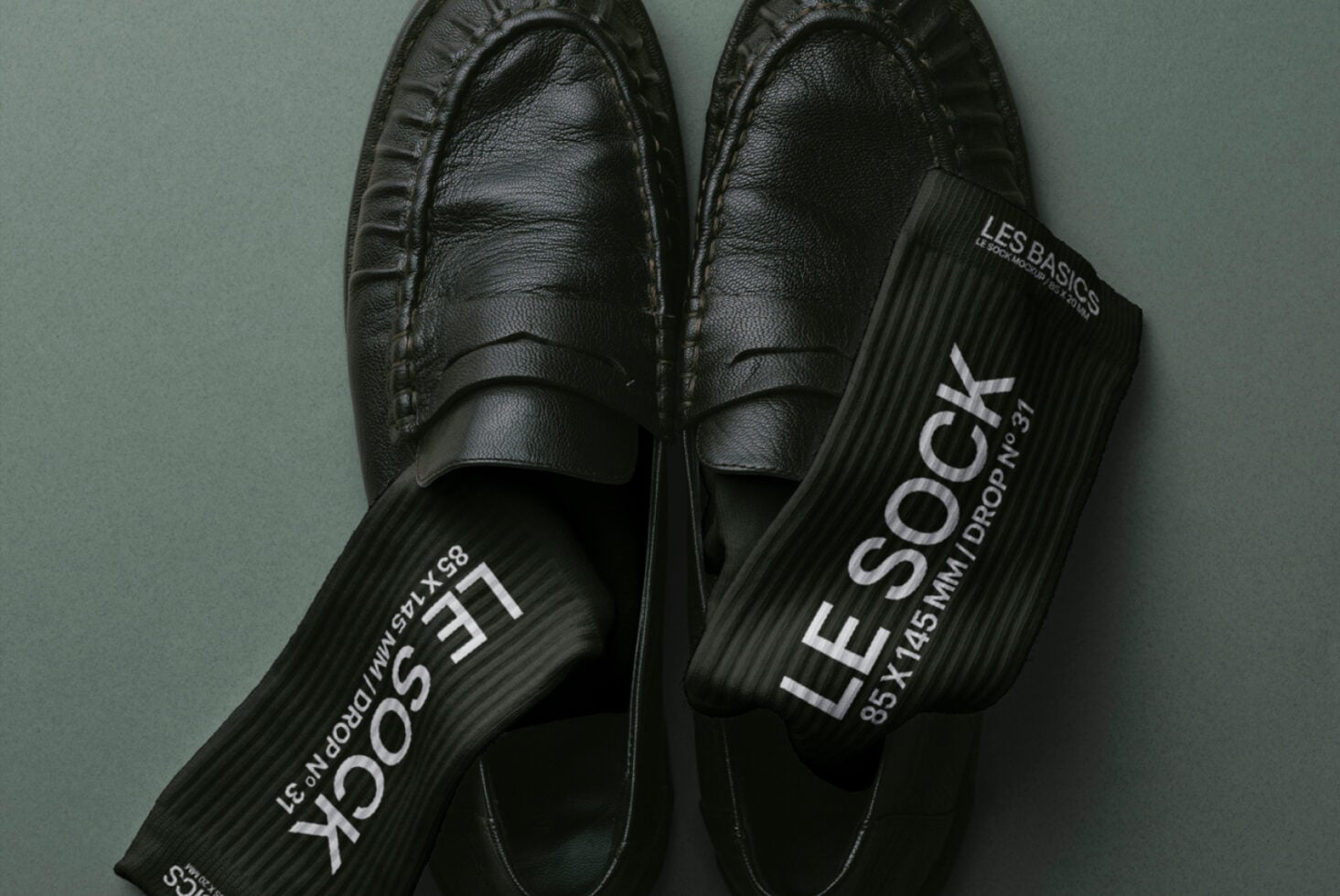 Top down view of black loafers with branded black socks draped across