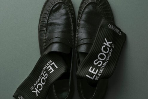 Top down view of black loafers with branded black socks draped across