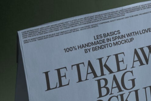 Angled view of white tote bag mockup with large serif text on green surface