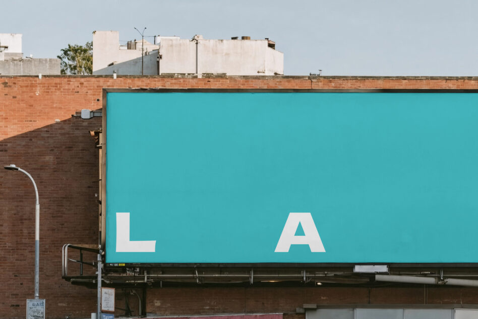 Bright turquoise billboard with large white L A letters on brick building