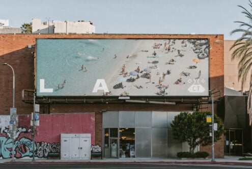 Billboard showing aerial beach photo with L A CT text overlay above storefront