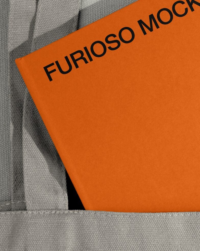 Orange card mockup partially tucked into gray fabric fold, minimal styling
