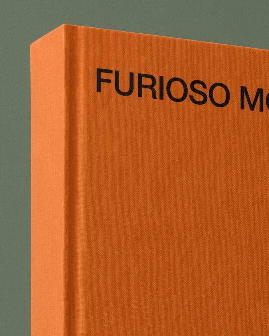 Side view of thick orange hardcover book mockup against teal background