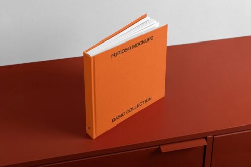 Bound orange hardcover book with visible white pages sitting on table