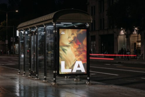 Bus shelter ad at night showing warm-toned movie poster with large LA text