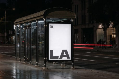 Nighttime bus shelter mockup with blank white display panel showing LA text