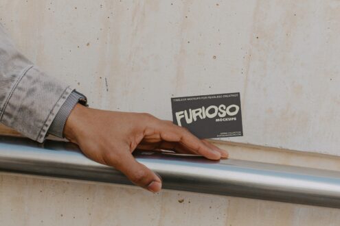 Hand on metal rail holding dark card with cream FURIOSO text