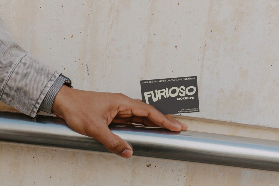 Hand on metal rail holding dark card with cream FURIOSO text