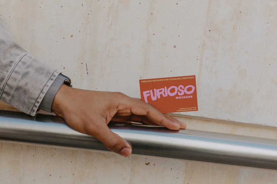 Hand on metal rail holding rust card with pink FURIOSO text