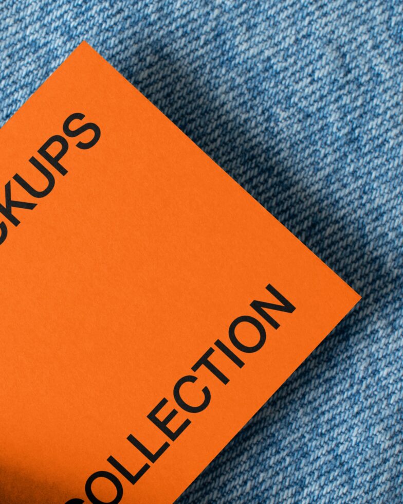 Bright orange card mockup placed on blue woven fabric texture closeup