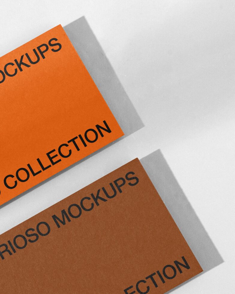 Two stacked paper mockups in orange with brown tone, casting shadows on white
