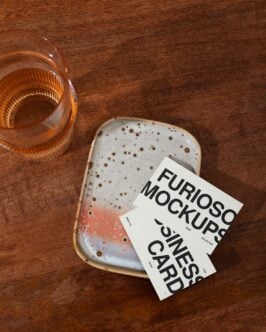 White folded cards displayed on rustic ceramic next to whiskey glass setup