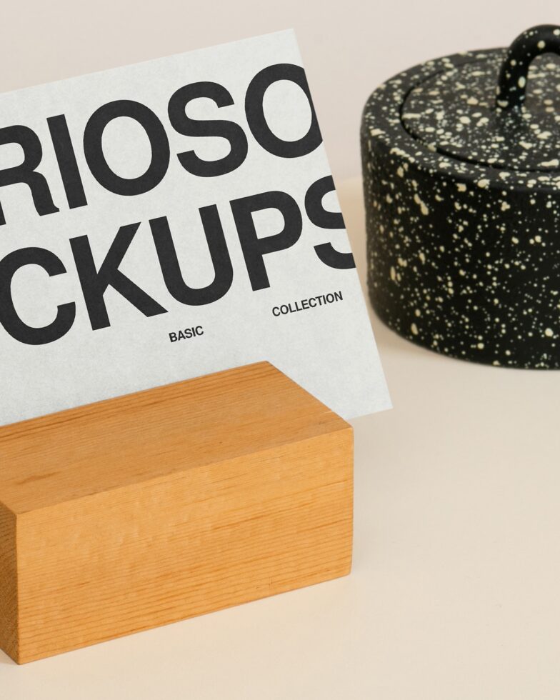 White card mockup leaning on wooden block next to speckled black pot