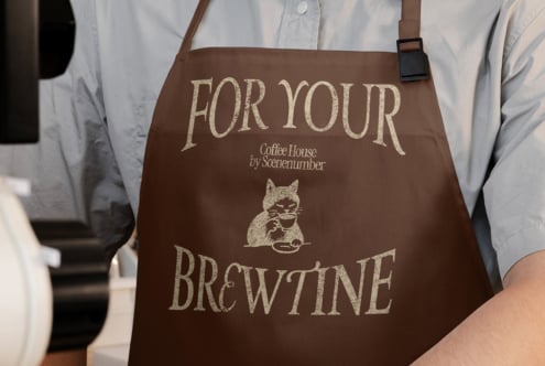 Brown apron with For Your Brewtine text, cat drinking coffee illustration, cream lettering