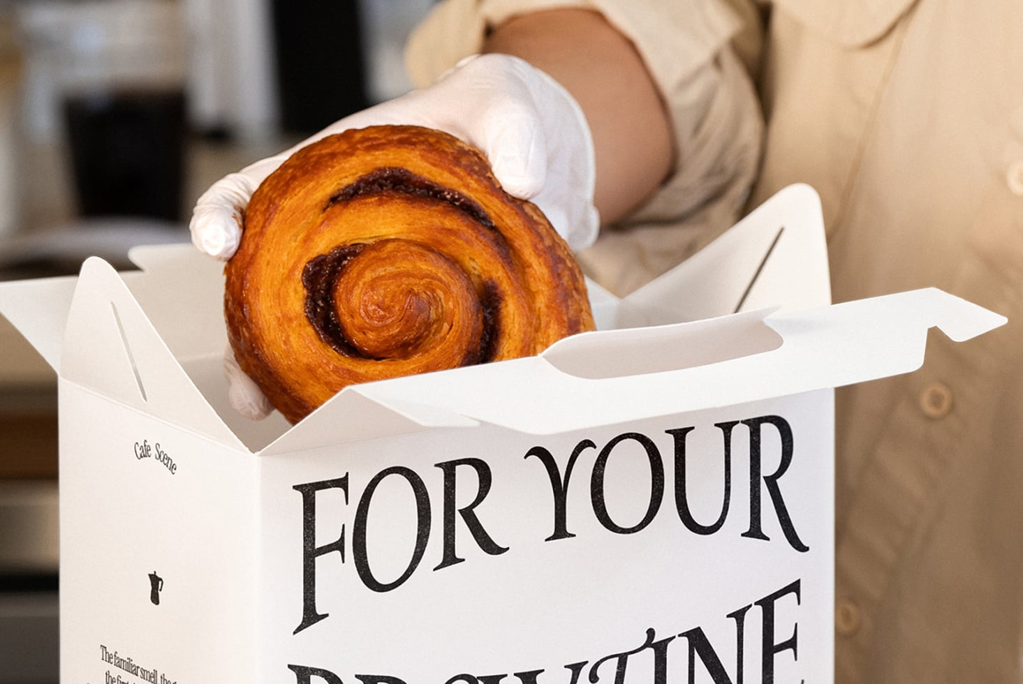 Chocolate croissant in white box with FOR YOUR text, held by hands in beige