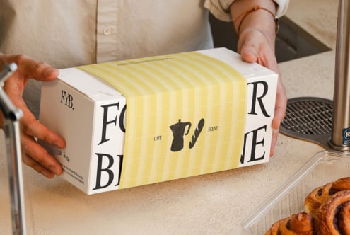 Person holding box with yellow striped sleeve paper wrapping around it