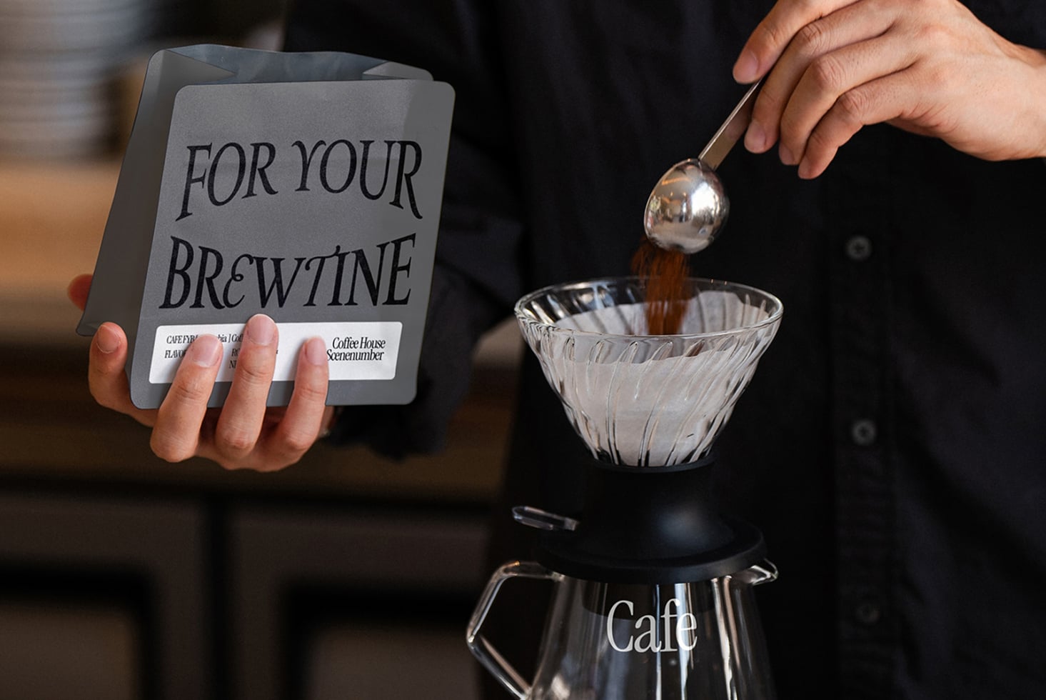 Hand pouring espresso from spoon into glass bowl, coffee branding card in background