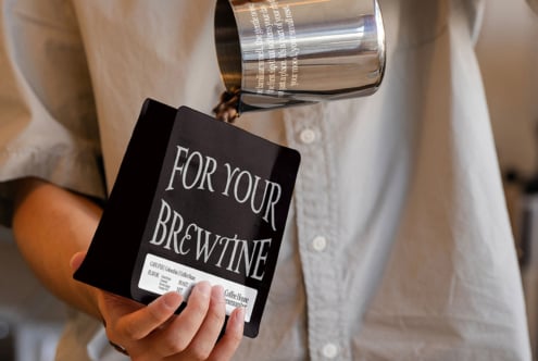 Black coffee bag mockup pouring into glass with silver canister overhead
