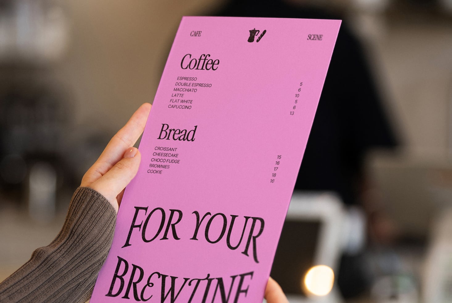 Hand holding bright pink menu with coffee, bread items, browline typography