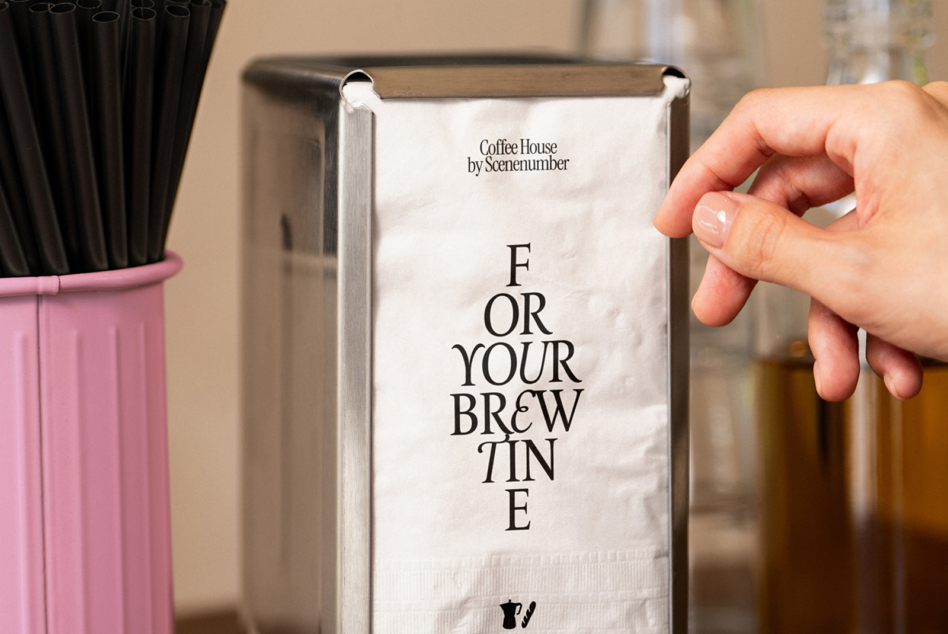 Hand holding white napkin mockup with coffee house branding from Scenenumber