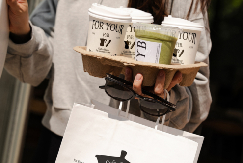 Cream colored cups in cardboard carrier with sunglasses, white shopping bag mockup