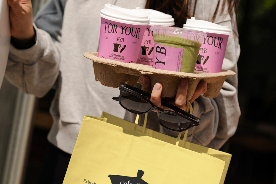 Pink coffee cups in cardboard carrier with yellow shopping bag mockup held by woman