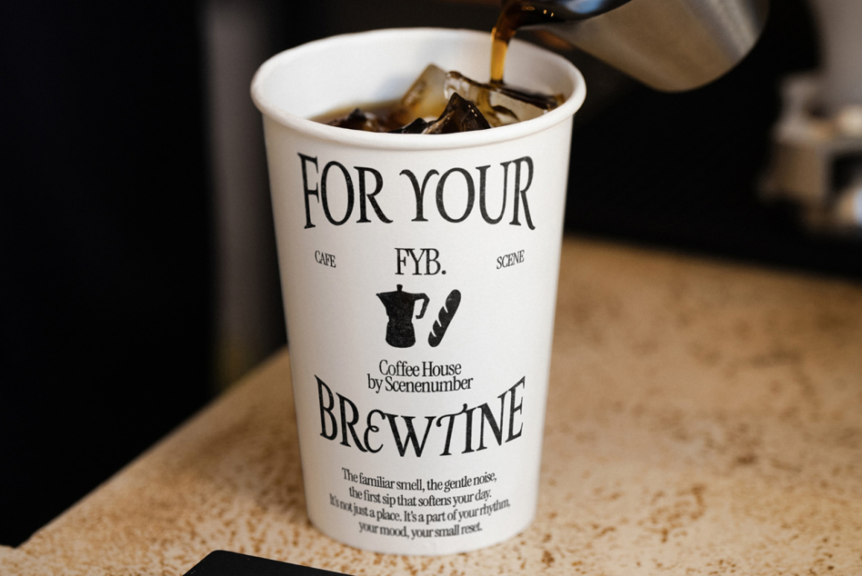 Hand pouring espresso into white cup labeled For Your FYB Brewtine by Coffee House