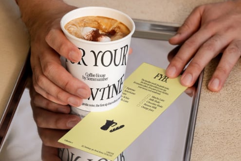 Cappuccino with latte art held next to yellow menu card with coffee cup icon