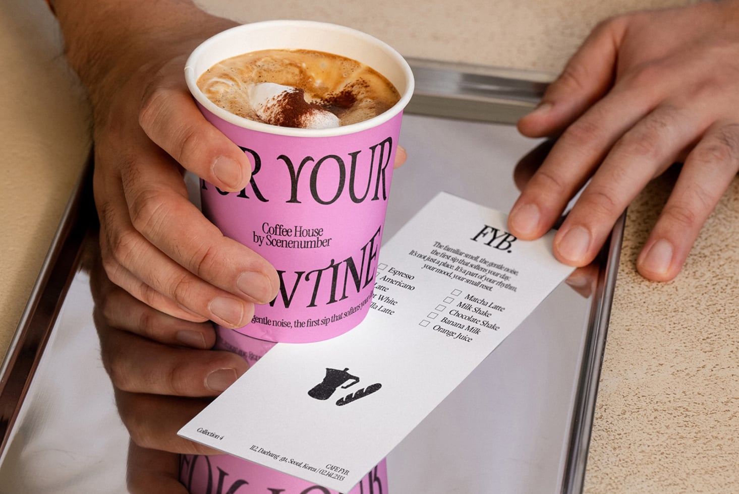 Hands holding bright pink paper coffee cup with menu card showing drink options