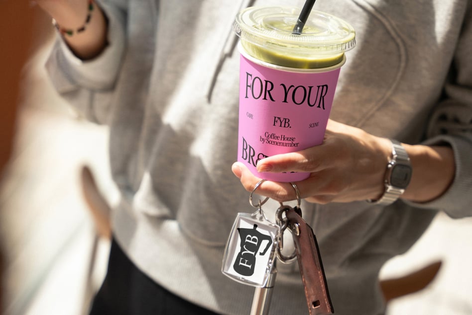 Hands placing clear lids on two FYB cups with green, brown drinks inside
