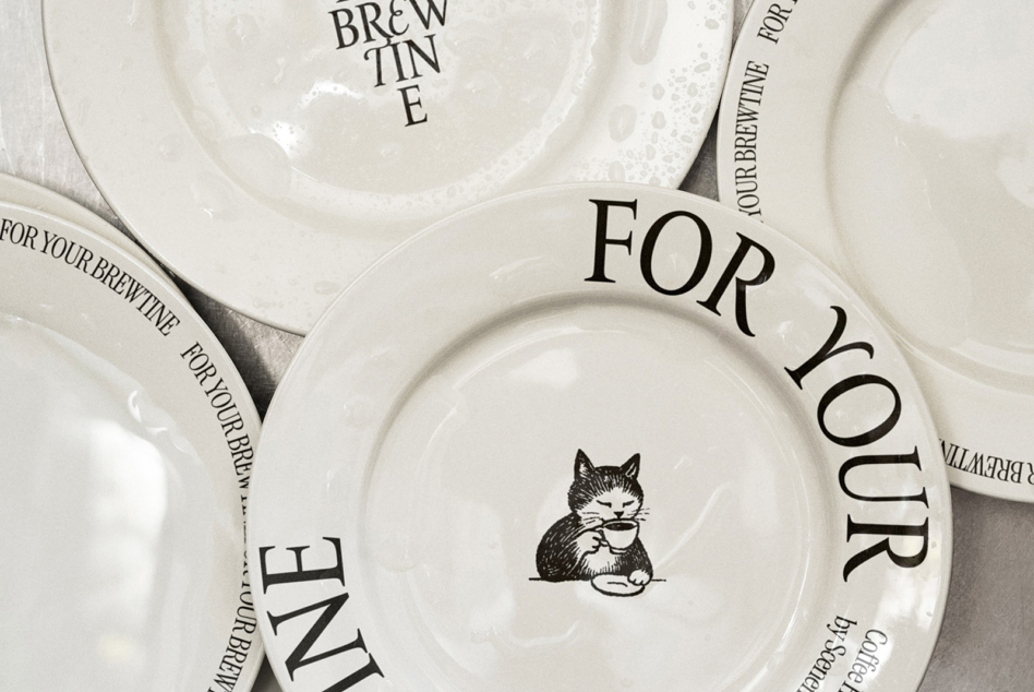 Cream colored stacked plates with cat holding cup, For Your Brewtine text on rim