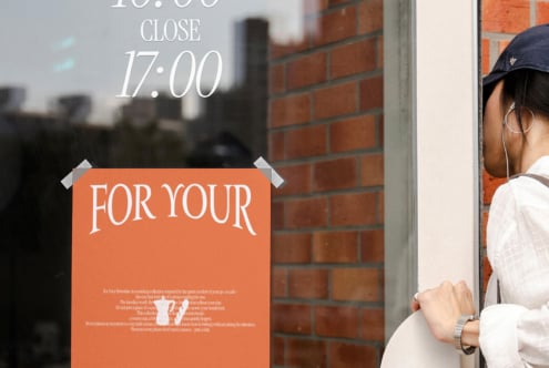 Window poster with orange panel reading For Your, white serif text above showing store hours