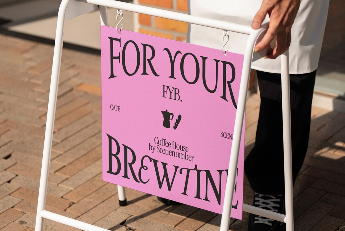 White A-frame with pink cafe sign mockup shown on outdoor brick plaza