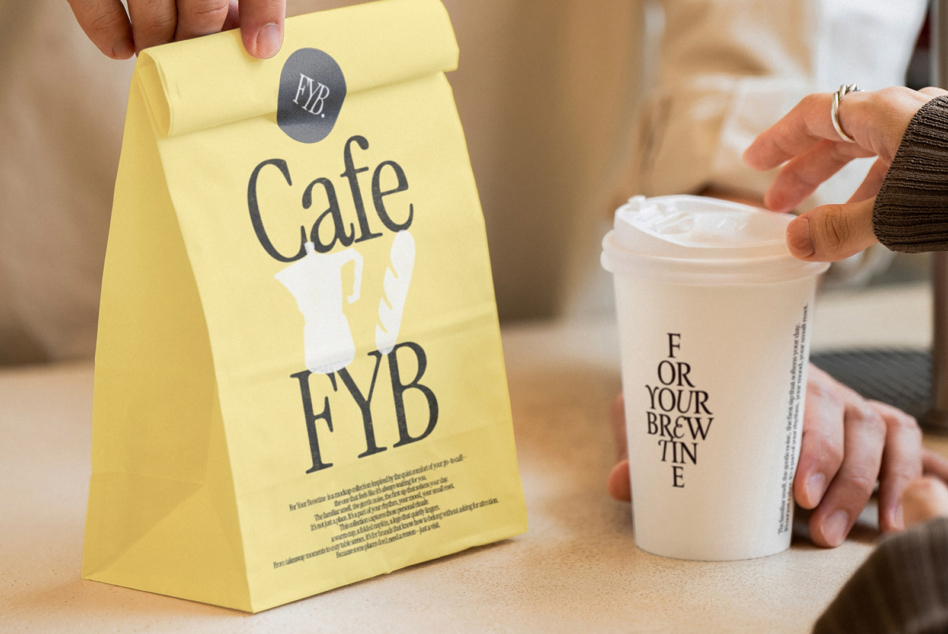 Yellow paper bag with Cafe FYB design held beside white branded cup