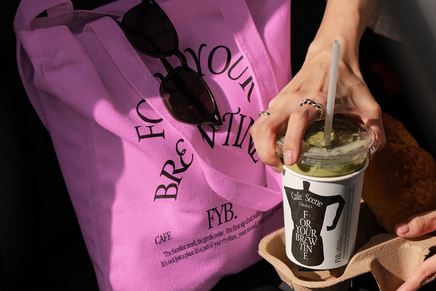 Pink tote with coffee house text next to iced drink cup on wooden surface