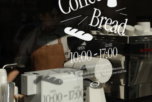 Bakery window mockup displaying coffee shop hours with editable text layout