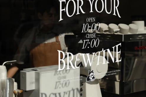 Cafe window decal mockup showing brewery branding with hours overlay