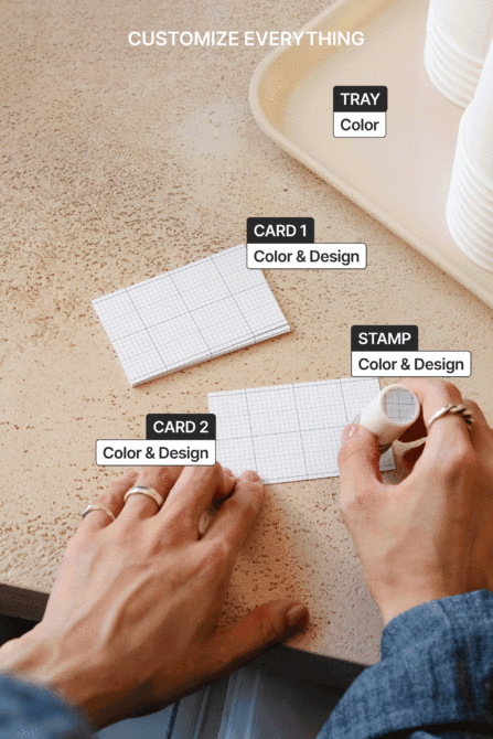 Overhead shot of cork surface with cream tray, grid cards, rubber stamp with heart design
