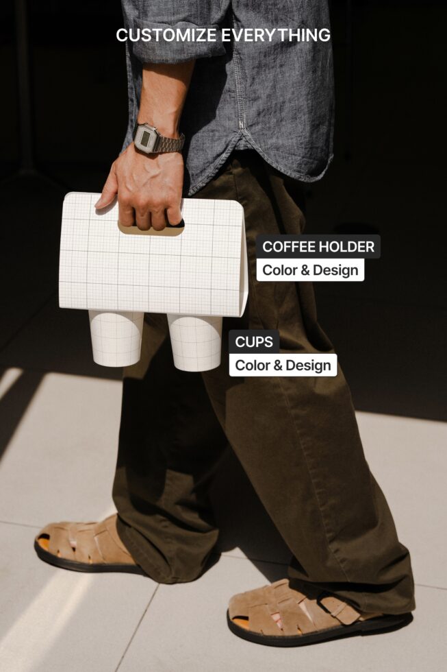 Person carrying grid-pattern coffee holder with two white cups, styled outfit shot