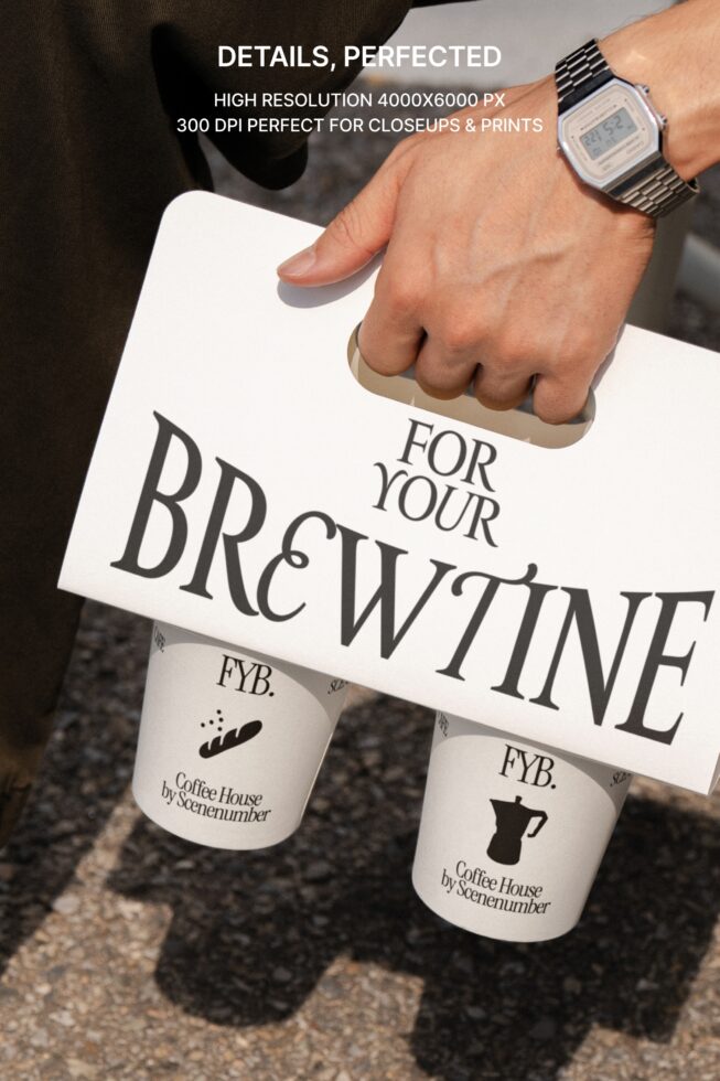 Hand holding white paper bag with metal watch, two coffee cups visible below