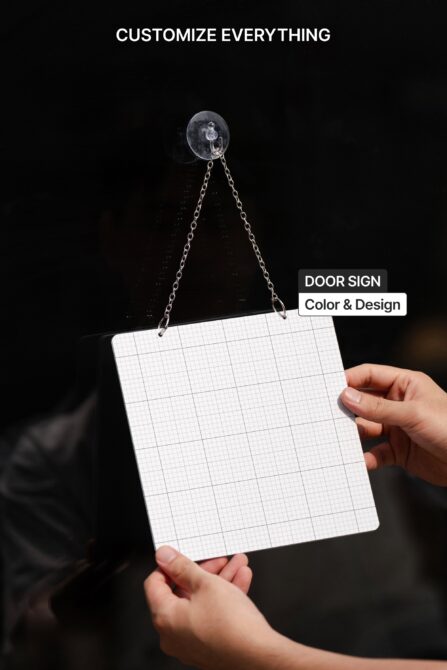 Hands holding blank grid paper door sign on chain against dark black background