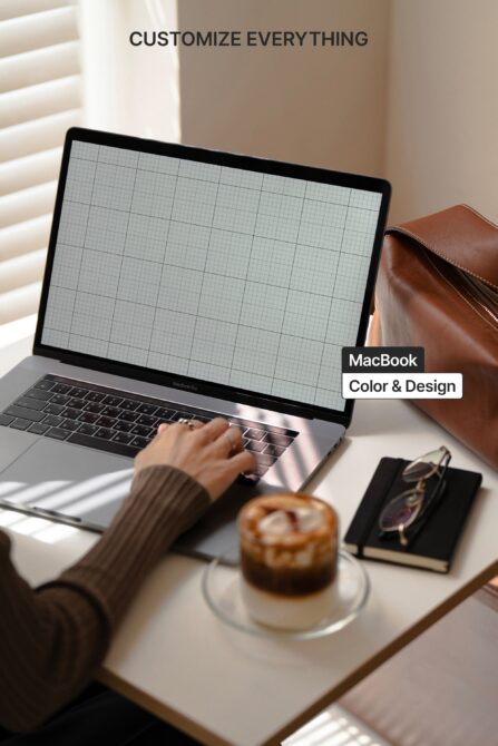 MacBook with blank grid screen on desk next to leather bag, coffee, notebook