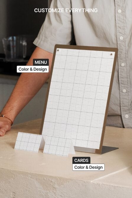 Wooden menu stand with grid paper held by person in cream shirt, small business cards