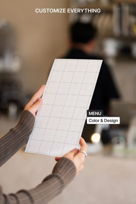 Woman holding blank grid menu card in casual cafe setting with soft lighting