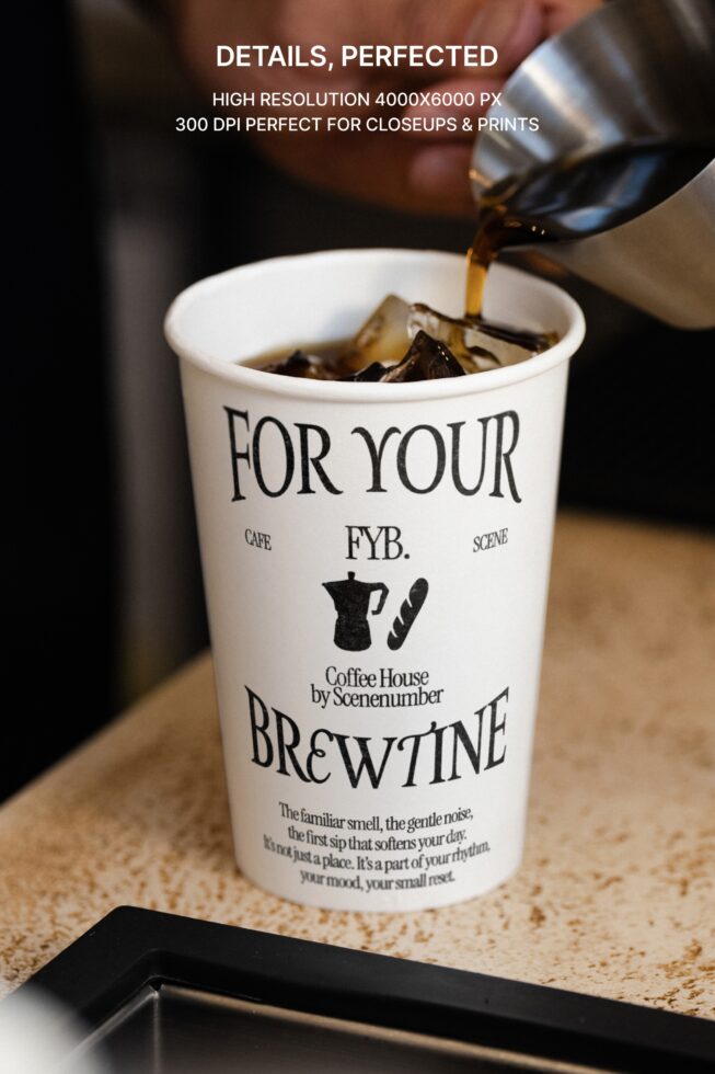 Golden espresso shot being poured into white paper cup on wooden surface
