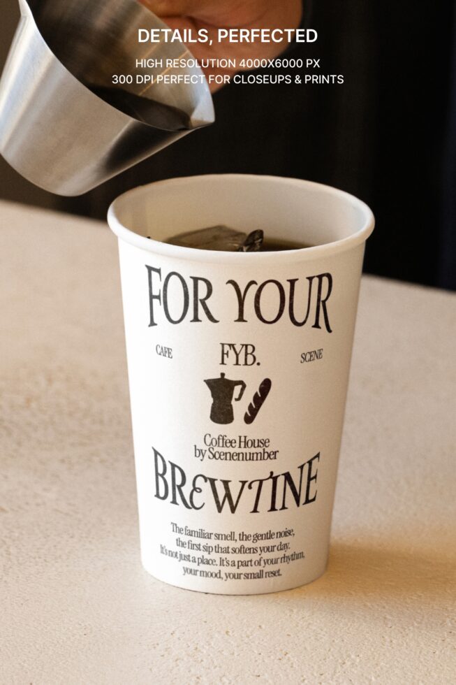 White paper coffee cup with black serif typography pouring espresso into it