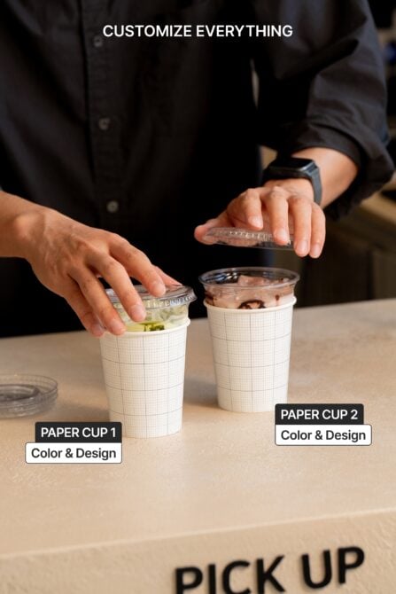 Two paper cups with lids being held, one with green tea, one with chocolate