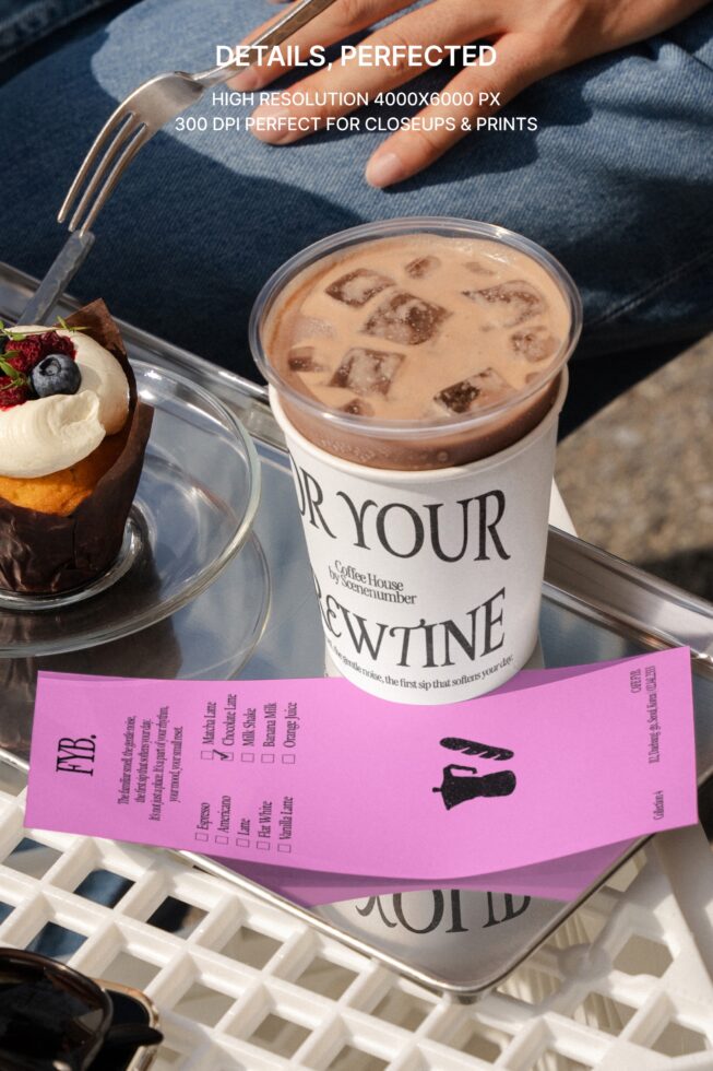 Fork beside iced coffee cup, pastry with cream berry topping, pink order form on tray